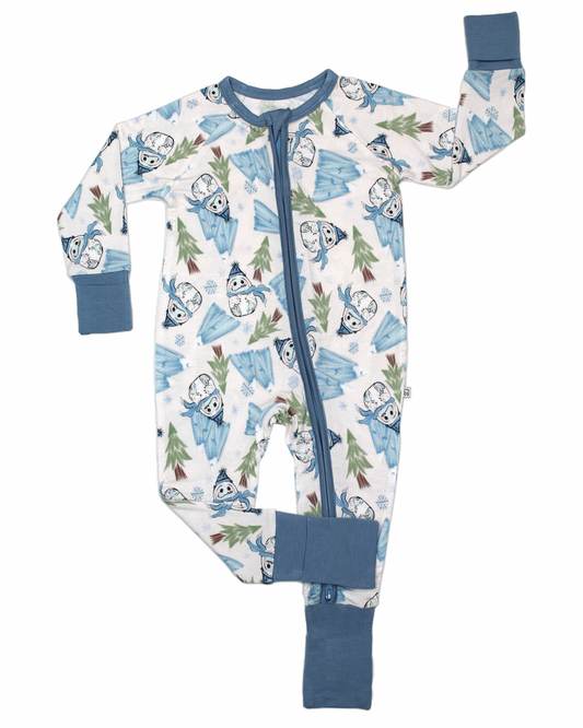 The Abominable Snowman • Bamboo Zippy (Updated Fit) is a baby onesie with blue cuffs and zipper, featuring mountains, trees, snowflakes, and cartoon polar bears on white bamboo fabric.