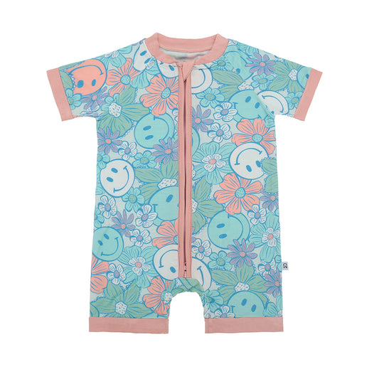 The Pastel Hippie • Bamboo Shorty (Classic Fit) is a soft bamboo romper with blue, teal, and peach smiley face florals, peach trim, and a front zipper for easy wear.