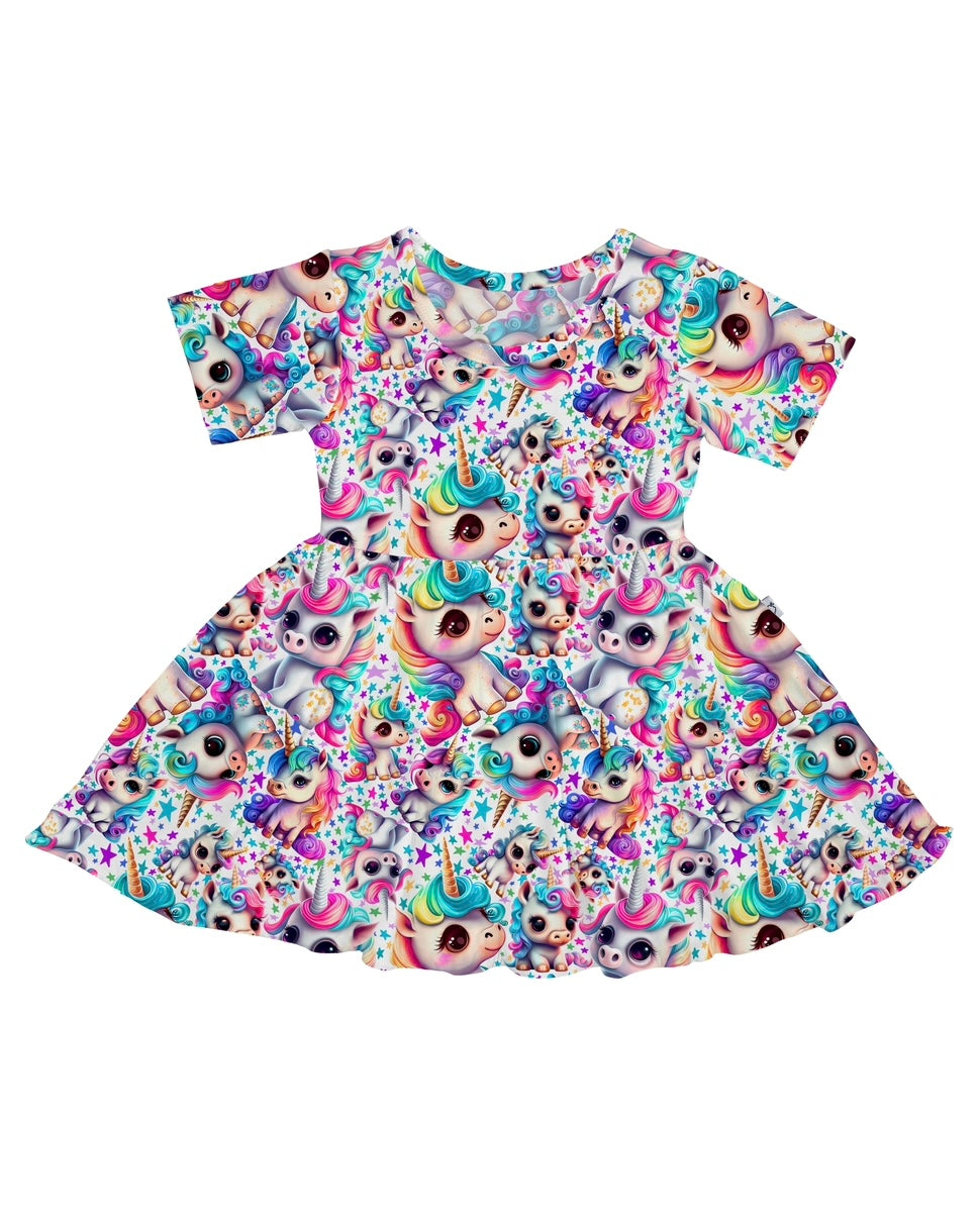 The Mythical Unicorns • Twirl Dress is a short-sleeve, flared skirt dress made from soft bamboo viscose, featuring a vibrant all-over print of cartoon unicorn faces, stars, and rainbows for comfort and playful style.