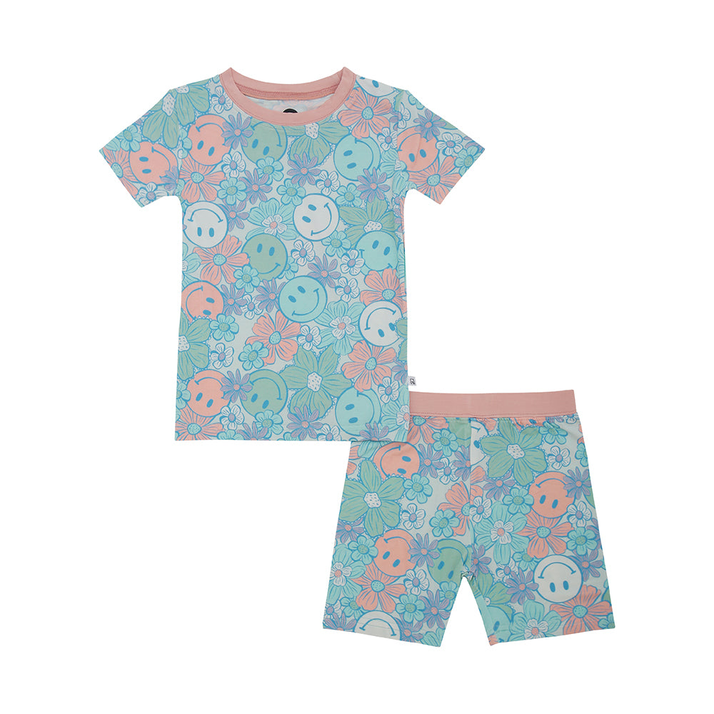 The Pastel Hippie • Short Sleeve Set (Classic Fit) features a light blue bamboo viscose fabric with pastel pink trim, decorated with playful blue and pink smiley faces and flowers—ideal for eczema-prone skin.