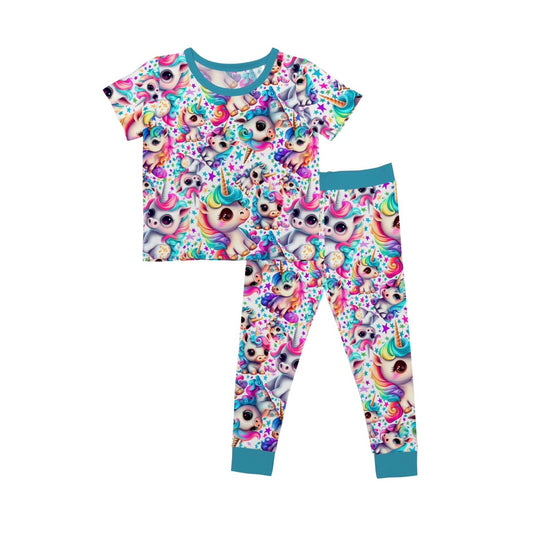 The Mythical Unicorns • 2 Piece Bamboo Set (Updated Fit) is a colorful kids’ pajama set with soft bamboo viscose, short-sleeve top and pants decorated with vibrant cartoon unicorn faces, confetti, stars, and blue trim on edges.
