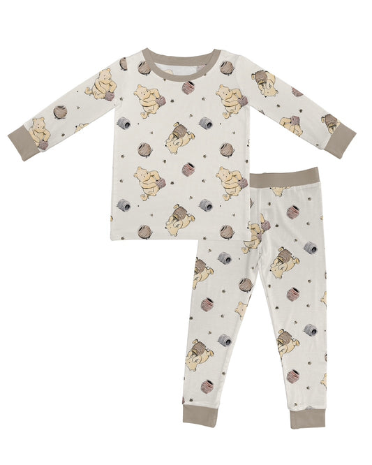 The Classic Pooh • 2 Piece Bamboo Set (Updated Fit) features a children’s long-sleeve top and pants in soft, stretchy fabric with a beige background, playful bear cubs with yarn, and light brown cuffs, collar, and ankle bands.