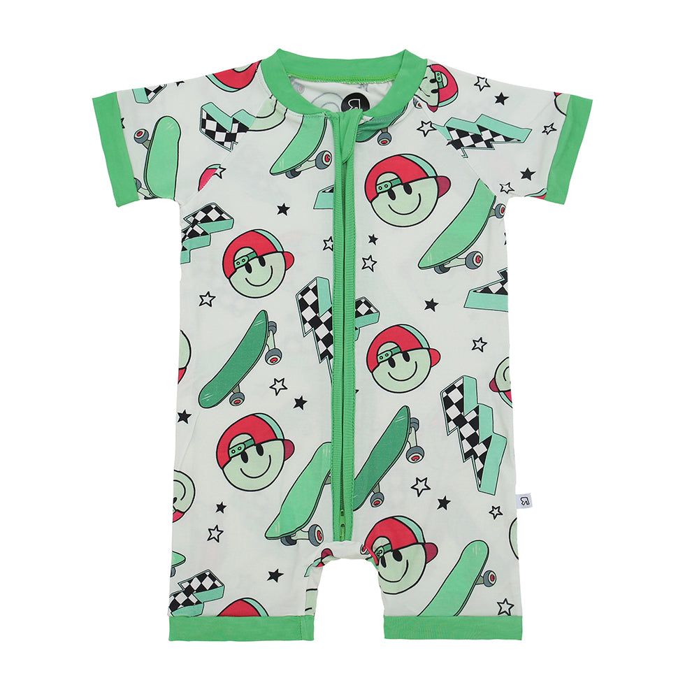 The Later Skater • Bamboo Shorty (Classic Fit) is a soft, short-sleeve romper with green trim, zipper front, and a playful skateboards print with red-capped faces, black stars, and checkered flags—ideal for sensitive skin.