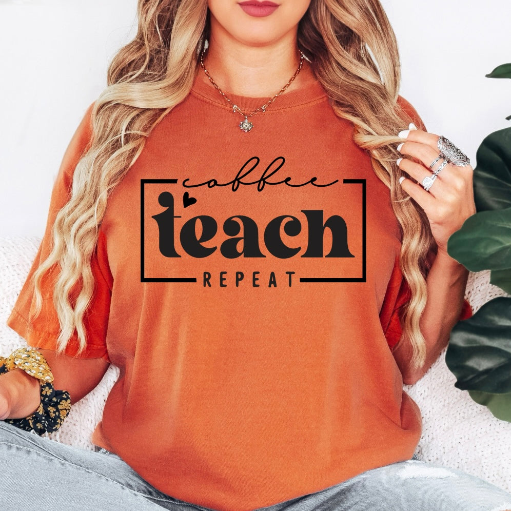 A woman with long, wavy blonde hair wears the Coffee Teach Repeat • Comfort Colors Tee in orange, featuring black lettering. She accessorizes with rings and bracelets while holding her hair.