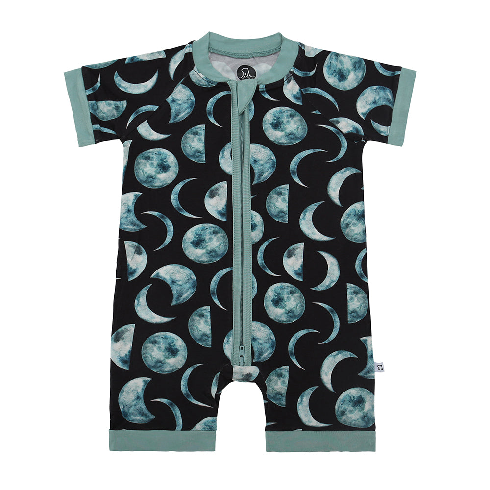 The Moon Child • Bamboo Shorty (Classic Fit) is a short-sleeved baby romper with a zipper front, blue-green moon phase pattern on a dark background, and green trim—crafted from bamboo viscose for cozy comfort.