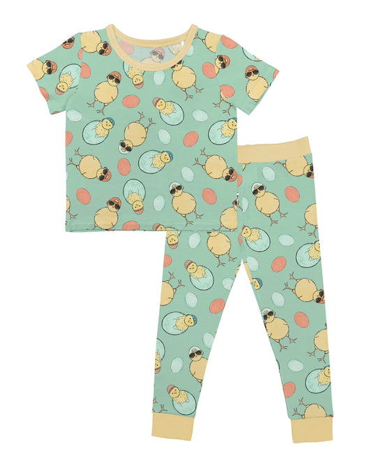 The Cool Chick • 2 Piece Bamboo Set (Updated Fit) features a soft bamboo fabric with a light green base, yellow chicks, and colorful eggs. Includes a short-sleeve top and pants with light yellow cuffs and collar—ideal for sensitive skin.