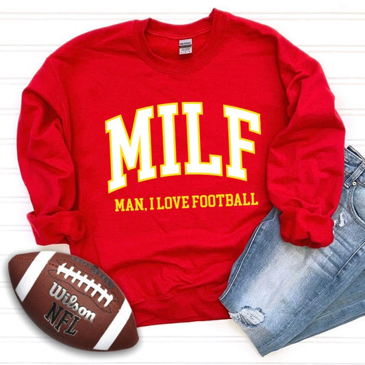 The MILF • Sporty Red Crew is a bold unisex sweatshirt in a cotton-poly blend, featuring yellow and white MILF text—Man, I Love Football. Pair it with blue jeans and an NFL Wilson football for the perfect sporty look.
