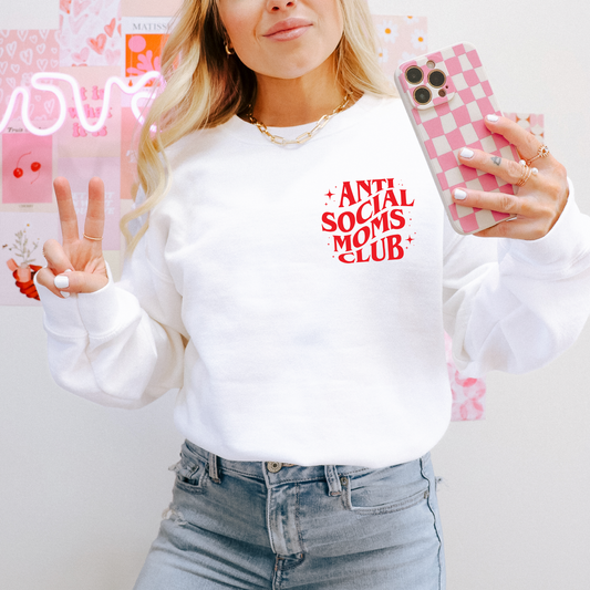 A woman takes a mirror selfie flashing a peace sign in the Anti-Social • Red & White Crew, paired with light blue jeans and holding a pink checkered phone, standing against pink wall decor.