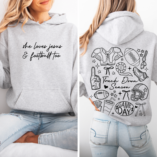 A woman wears the Jesus & Football • Ash Hoodie, a cozy unisex fit with “she loves jesus & football too” on the front and fun football doodles with phrases like "Touch Down Season" and "Game Day" on the back.