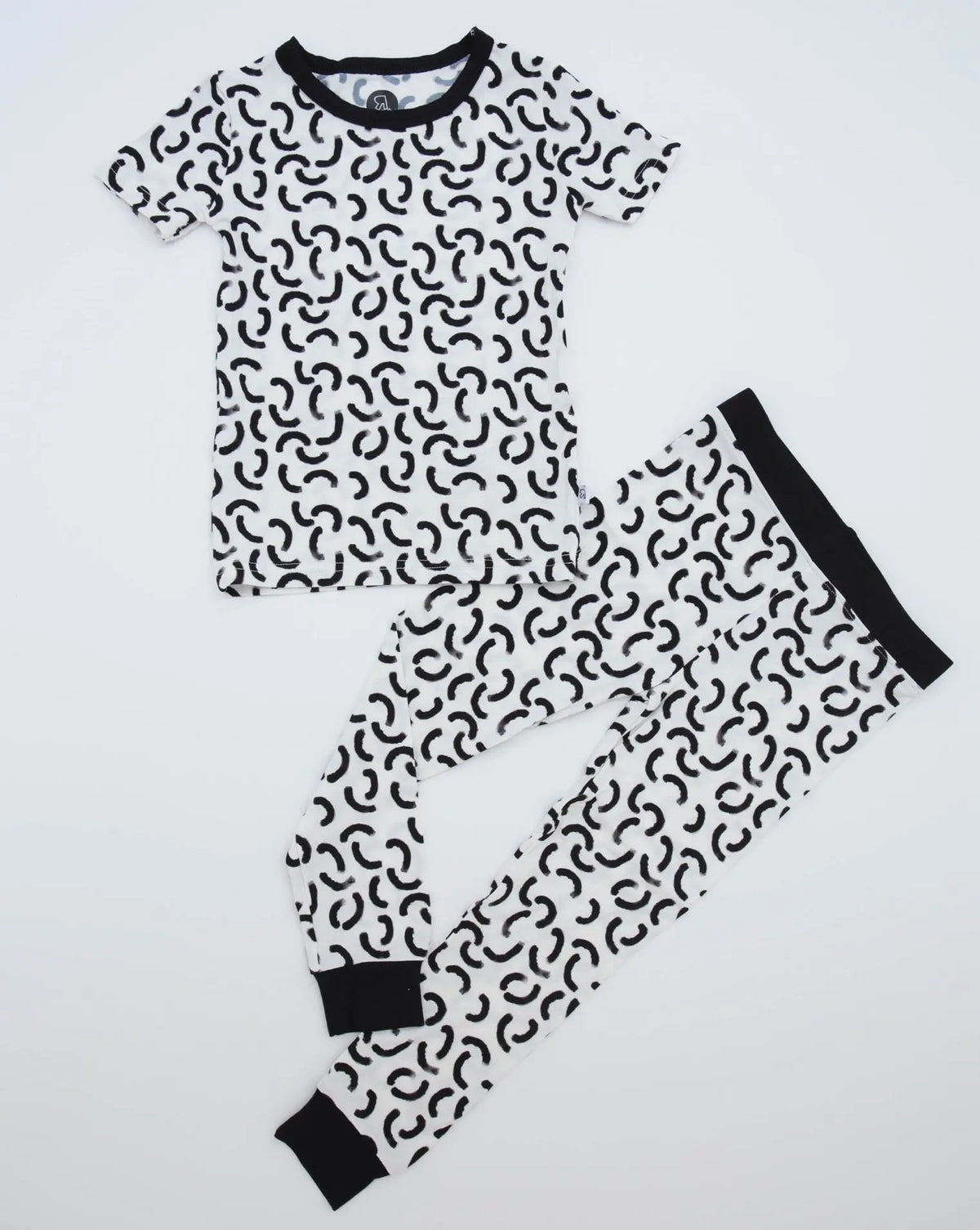 The Monochrome • 2 Piece Bamboo Set (Classic Fit) includes a short-sleeve top and long pants in soft bamboo, with a white background, black abstract squiggles, and solid black cuffs—ideal for eczema-prone skin.