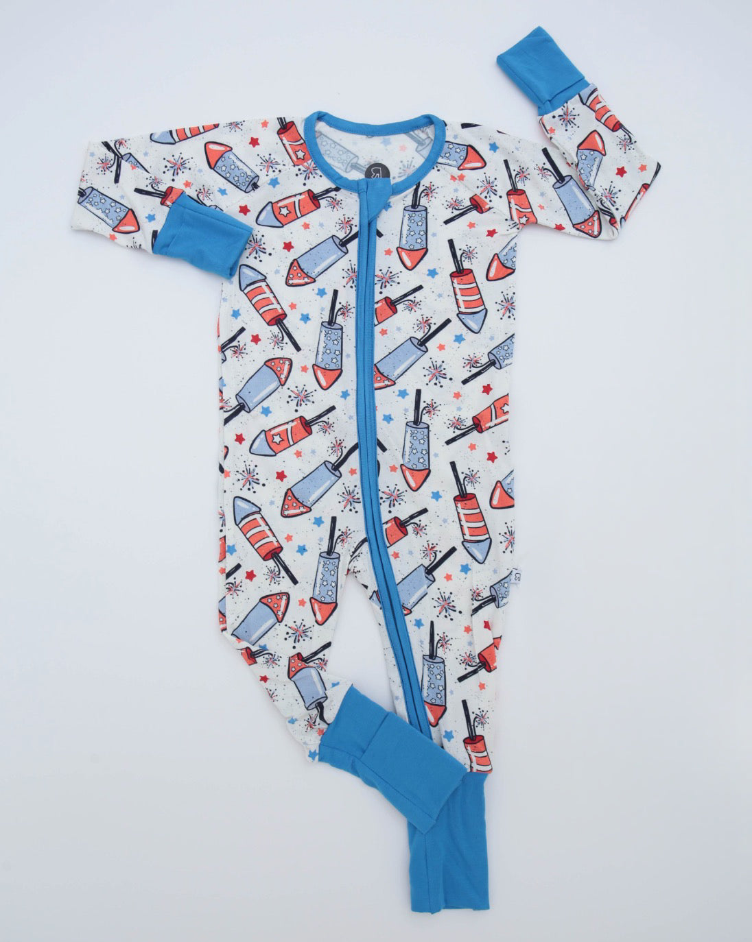 The Youre a Firework • Bamboo Zippy (Classic Fit) is a soft bamboo onesie with a red, white, and blue popsicle and fireworks pattern, blue cuffs on sleeves and ankles, and a front blue zipper.
