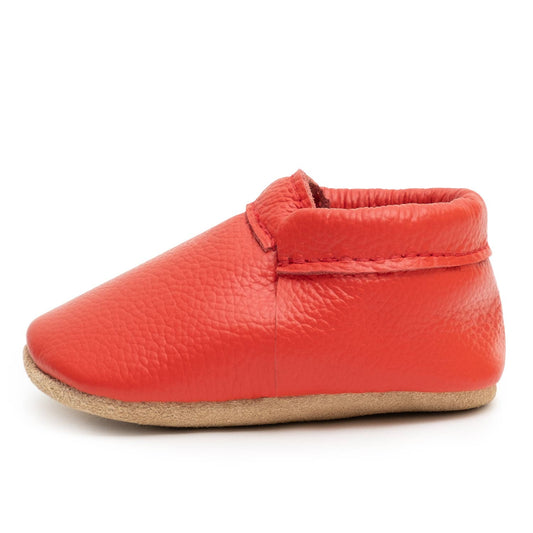 A single Red • Fringeless Moccasin made of genuine leather with a soft tan sole is shown in side profile on a white background.