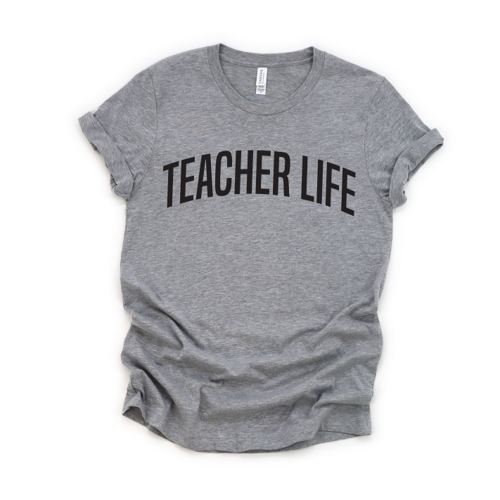 The Teacher Life • Gray Tee Shirt features bold black TEACHER LIFE text on a gray Bella/Canvas unisex T-shirt with rolled sleeves, shown laid flat on a white background.