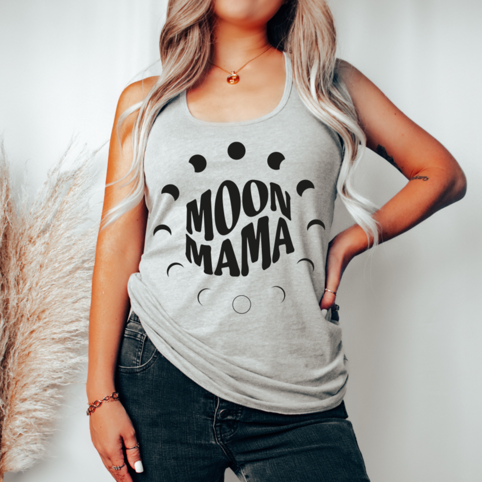 A woman with long, wavy blonde hair models the Moon Phase Mama • Unisex Tank Top in gray, featuring MOON MAMA text surrounded by moon phases. She stands casually with one hand on her hip against a neutral background.