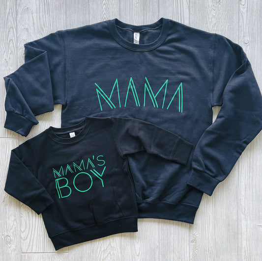 Mamas Boy Pullover • Black & Lime: Two black pullovers on a light wood floor—one adult-sized with MAMA in green, and one unisex child-sized with MAMAS BOY in green.
