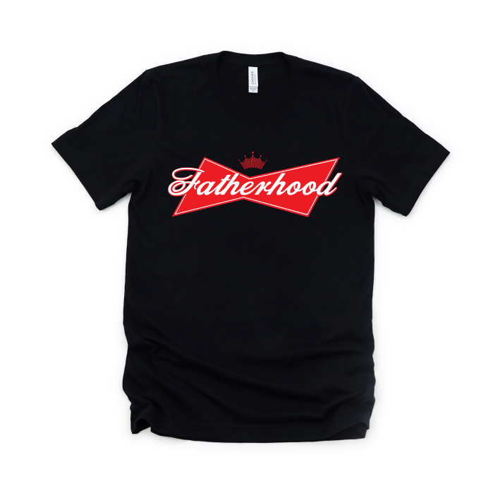 The King of Fatherhood • Black Tee features Fatherhood in white script inside a red bowtie-shaped logo with a crown, inspired by Budweiser. Made from soft combed and ring-spun cotton for unisex essential comfort.
