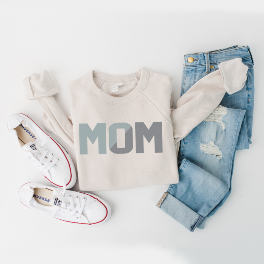Flat lay of the MOM sliced • Dusty Pullover—cream unisex sweatshirt with bold MOM print—styled with light blue ripped jeans and white Converse sneakers on a white background. This casual look suits everyone.