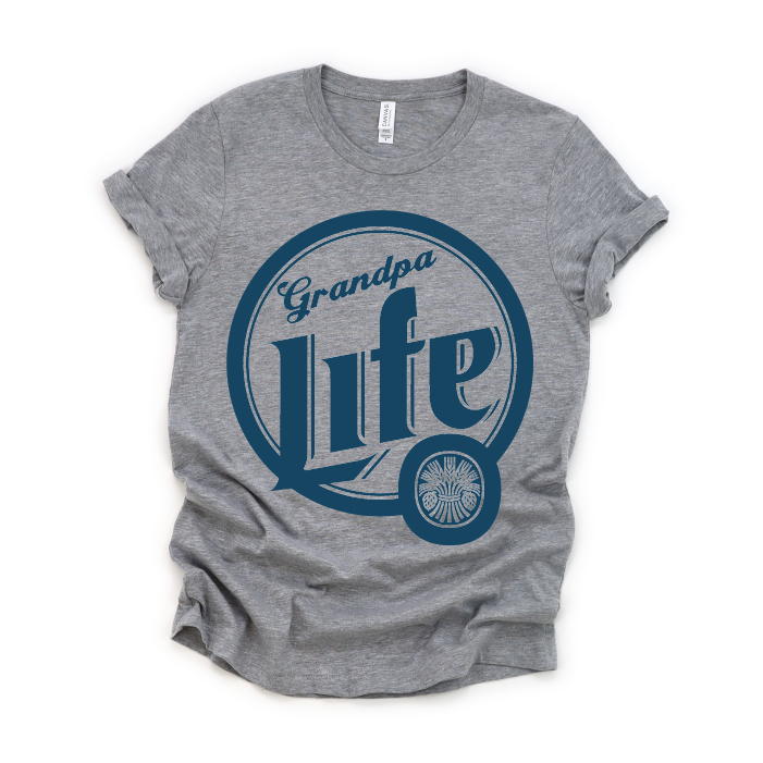 The Grandpa Life • Beer Tee is a gray crew neck t-shirt with rolled sleeves, made from soft ring-spun cotton. It features a large navy blue circle design, Grandpa Life in script, and a small wheel graphic at the lower right.