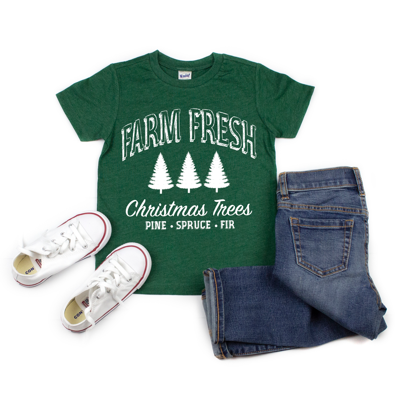 The Farm Fresh • Kids Tee is a green, tree farm-inspired shirt for kids with FARM FRESH Christmas Trees PINE • SPRUCE • FIR and three white tree graphics. Shown styled with blue jeans and red-accented sneakers. Available in various sizes.
