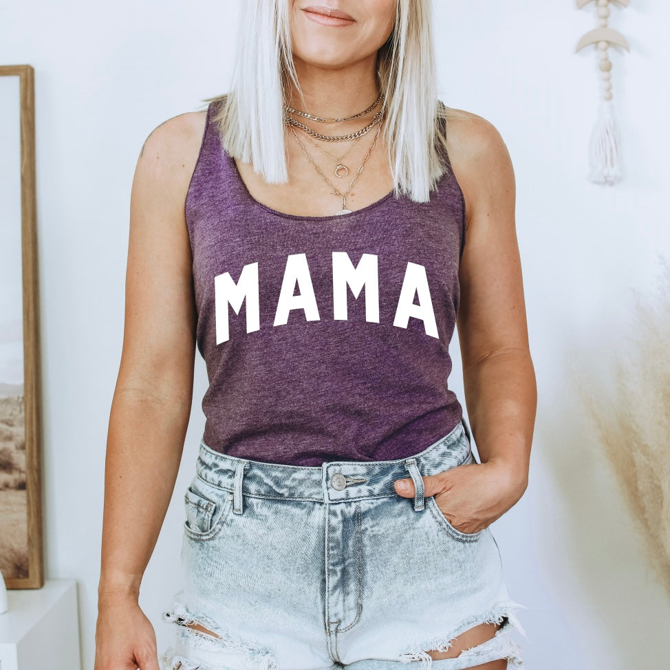 A blonde woman wears the MAMA • Vintage Purple Tank, a heather racerback top with a bold MAMA print, paired with distressed denim shorts and one hand in her pocket.