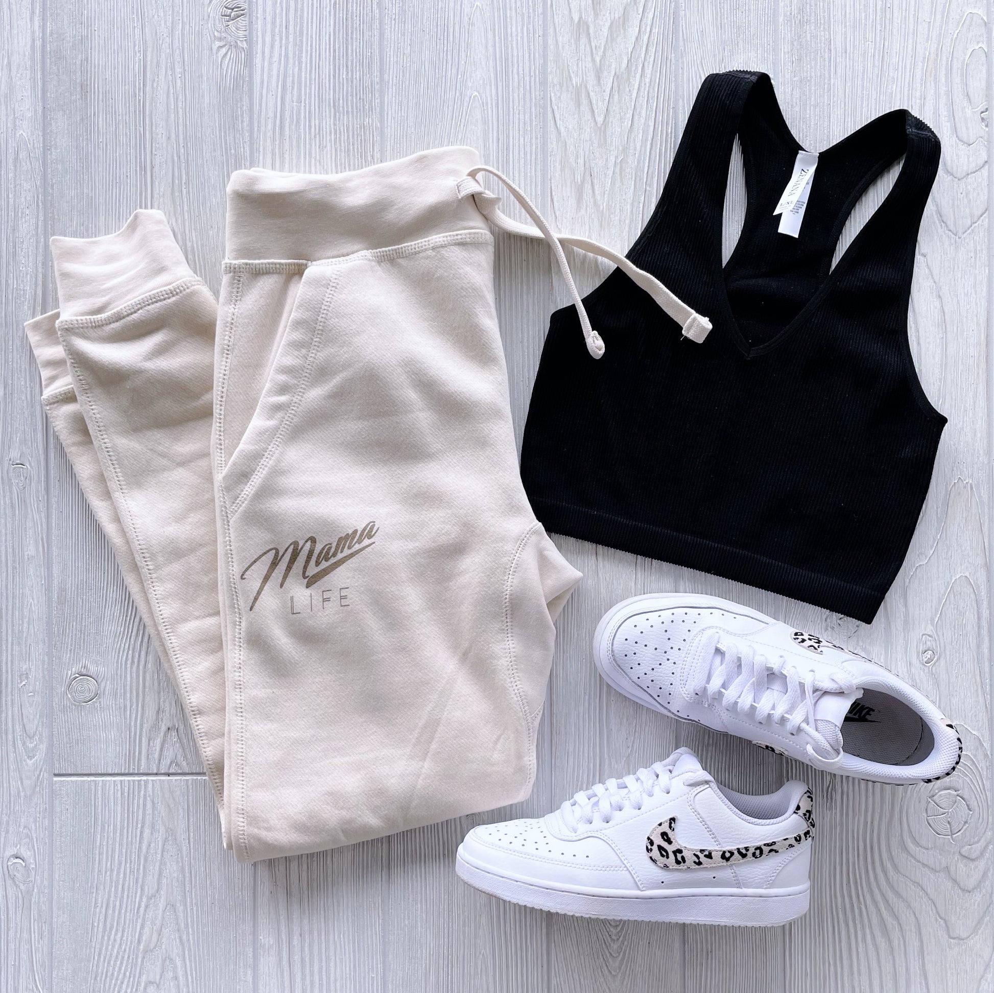 The Retro Mama Life • Sand Joggers are styled with a black sports bra and white sneakers featuring leopard print detail, making the perfect loungewear look on a light wood floor.