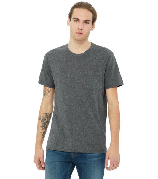 A young man with long light brown hair pulled back wears the Skater Dad • Asphalt Pocket Tee with blue jeans. He has tattoos on his left forearm and stands against a plain white background.