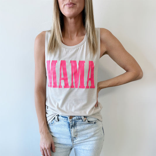A woman models the MAMA • Silver Scoop Tank, a sleeveless beige top with a relaxed fit and bold pink MAMA print, styled with light blue jeans against a plain white wall.