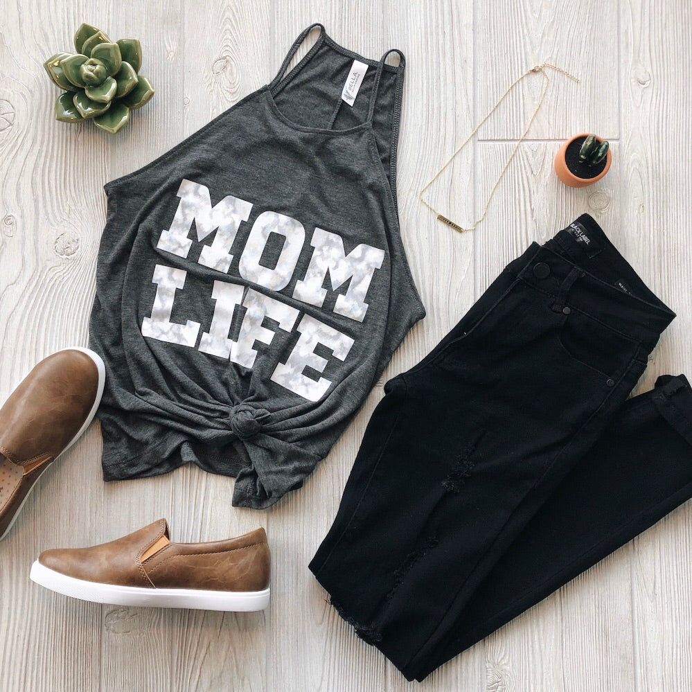A flat lay of the MOM LIFE Marble Print High Neck Tank with black jeans, brown slip-on shoes, a necklace, and succulents on a light wood floor—perfect for effortless women’s style.