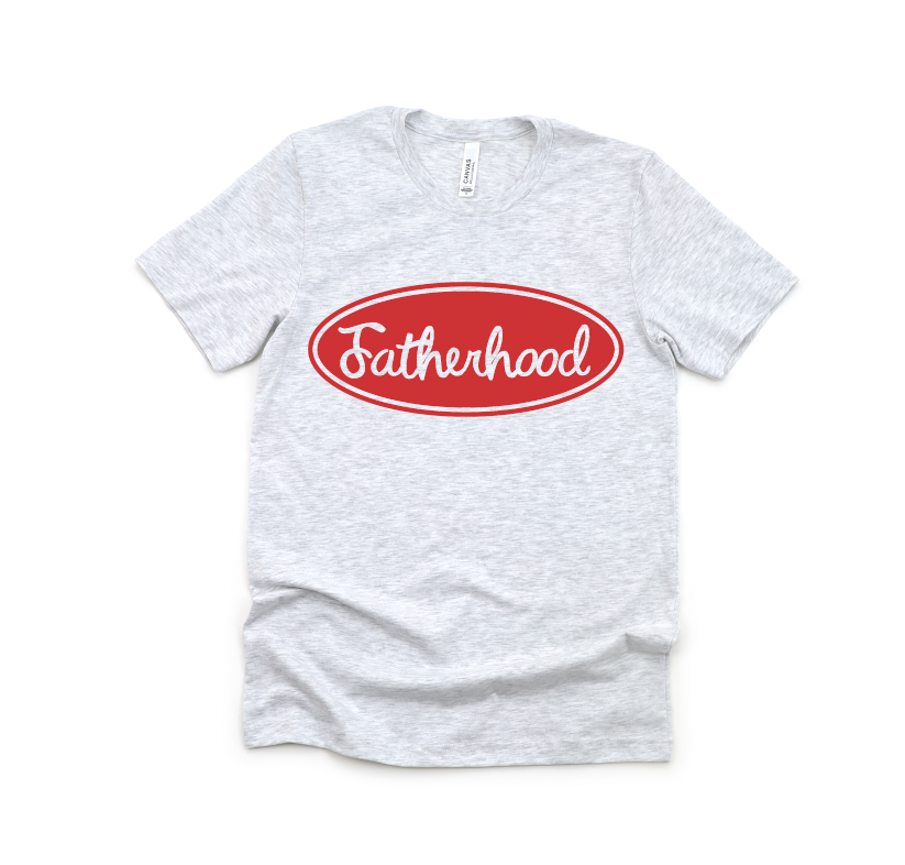 The Fatherhood Trucker • Ash Gray Tee is a light gray unisex crew neck T-shirt with a red oval on the chest displaying Fatherhood in white script, shown laid flat on a white background.