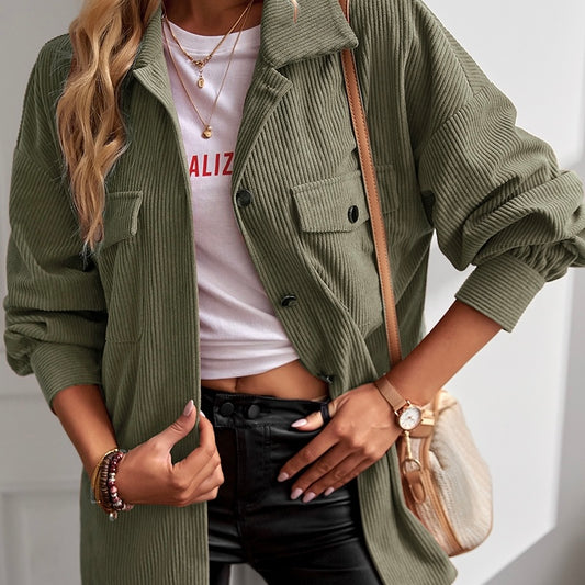 Someone styled the Cassandra Shacket in green over a white tee with red text, black pants, layered necklaces, bracelets, a watch, and a beige crossbody bag.